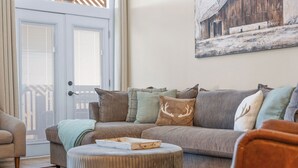 A living room with a grey sectional sofa, a round ottoman, and a painting on the wall. - Penthouse Table Rock Lake View  Near SDC (Branson)