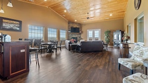 A spacious living room with a wooden ceiling, a stone fireplace, and a large window. - Penthouse Table Rock Lake View  Near SDC (Branson)