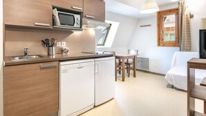Una cucina compatta con forno a microonde, lavastoviglie e un piccolo angolo ristoro con tavolo e sedie.