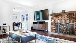 Una sala de estar moderna con un televisor de pantalla plana, una chimenea y un comedor con vistas al exterior.