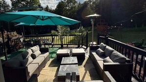 Un patio al aire libre con mobiliario de mimbre, un paraguas grande y una parrilla.