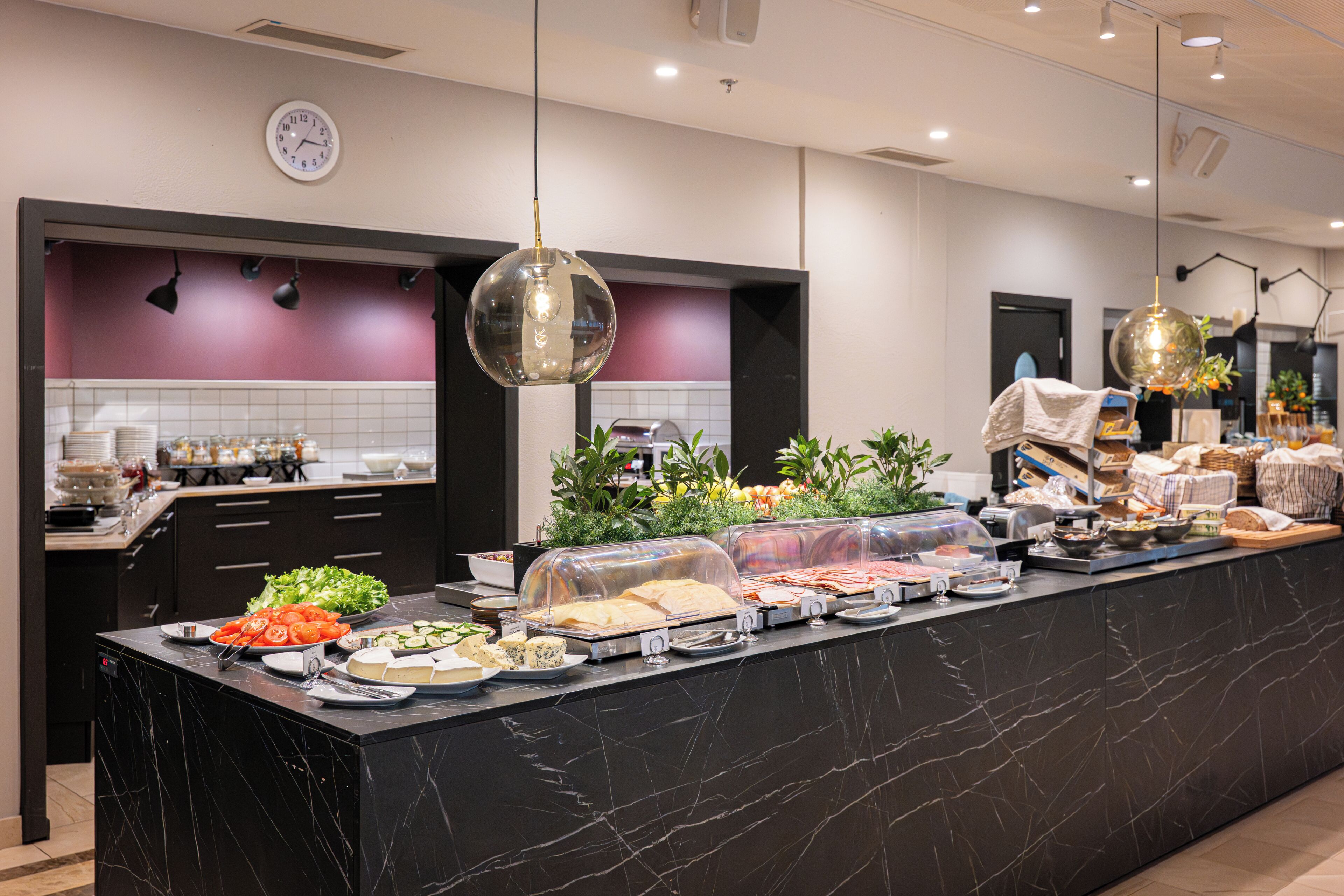 A modern kitchen with a marble countertop, a clock, and various food items.