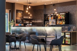 Een moderne bar met een marmeren toonbank, diverse zitmogelijkheden en een ruim assortiment aan drankjes.