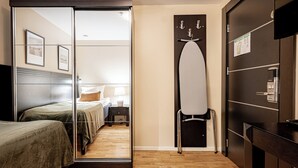A hotel room with a bed, a nightstand, a mirror, a wardrobe, and a door with a towel rack. - Injoy Compact Hotel Solna (Solna)