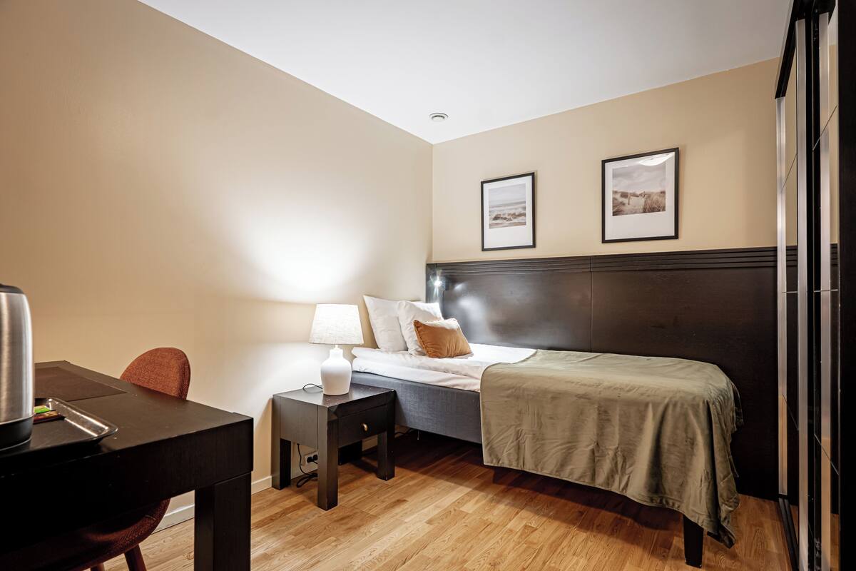 Une chambre d’hôtel avec un lit, une table de chevet, une lampe et un tableau au mur.