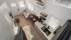 A compact kitchen with a dining area, a sofa, and a window with blinds.