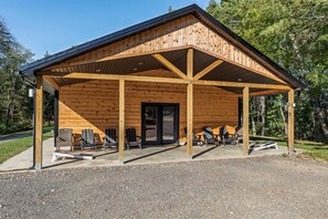 A wooden cabin with a covered porch, outdoor seating, and a door leading inside.