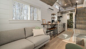 A modern interior with a sofa, kitchen area, and a loft space.