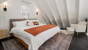Une chambre avec un grand lit, une fenêtre, une chaise et un tapis.