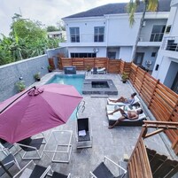 Uma área de piscina no terraço com espreguiçadeiras e um grande guarda-sol.