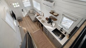 Eine kompakte Küche mit weißen Schränken, ein Essbereich mit Tisch und Stühlen sowie ein großes Fenster für natürliches Licht.