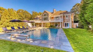Ett tvåvåningshus med en swimmingpool, en uteplats och en välskött gräsmatta.