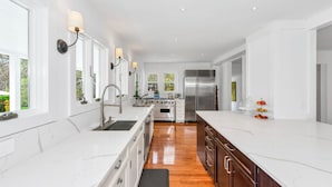 A modern kitchen with white cabinetry, stainless steel appliances, and a wooden floor. - Beautiful Shelter Island Getaway on over an acre, minutes from the ferry! (Shelter Island)
