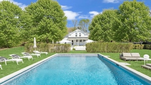 A swimming pool with lounge chairs, a house in the background, and well-maintained greenery. - Beautiful Shelter Island Getaway on over an acre, minutes from the ferry! (Shelter Island)