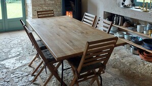 A rustic dining area with a large wooden table and chairs, a stone wall, and a fireplace. - Beautiful Lotoise house, located in a typical village. Large garden and swimming pool. (Le Vignon-en-Quercy)