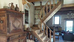 A rustic interior with a wooden staircase, a large cabinet, and a cozy seating area. - Beautiful Lotoise house, located in a typical village. Large garden and swimming pool. (Le Vignon-en-Quercy)