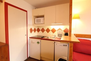 A compact kitchenette with a microwave, sink, and small refrigerator.