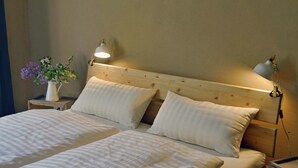 A double bed with white linens and two bedside lamps. - Pure tranquillity: vacation apartment close to nature in Unkengrund (Nordwestuckermark)