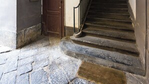 Eine Steintreppe mit Metallgeländer, die zu einer Tür am oberen Ende führt.