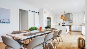 Una cocina moderna con armarios blancos, una isla central e iluminación colgante.
