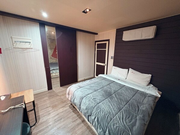 A bedroom with a bed, a desk, a wardrobe, and a door. - sharp motel (Jeju City)