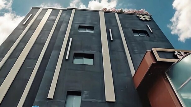 Ein hohes Gebäude mit modernem Design, das durch vertikale Linien und rechteckige Fenster gekennzeichnet ist.