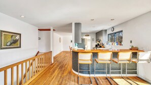 A spacious kitchen with a central island, wooden bar stools, and a wooden staircase.