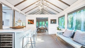 A spacious kitchen with a central island, a dining area with a large table, and a seating area with a sofa and chairs.