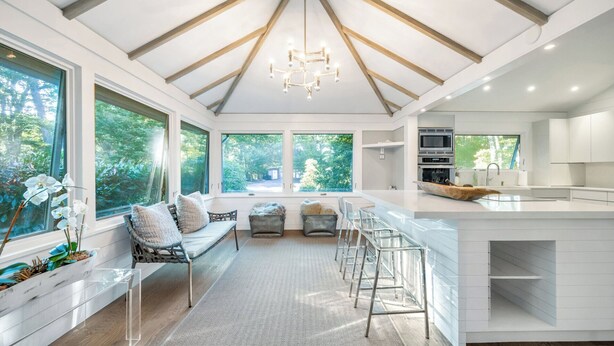 A modern kitchen with a large island, white cabinetry, and a view of the outdoors.