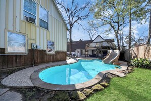 Enjoy a refreshing swim in the pool surrounded by a beautifully maintained lawn and a wooden fence.