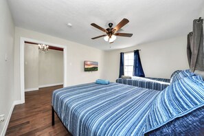 Relax in a spacious room with a large bed, ceiling fan, and window with curtains.