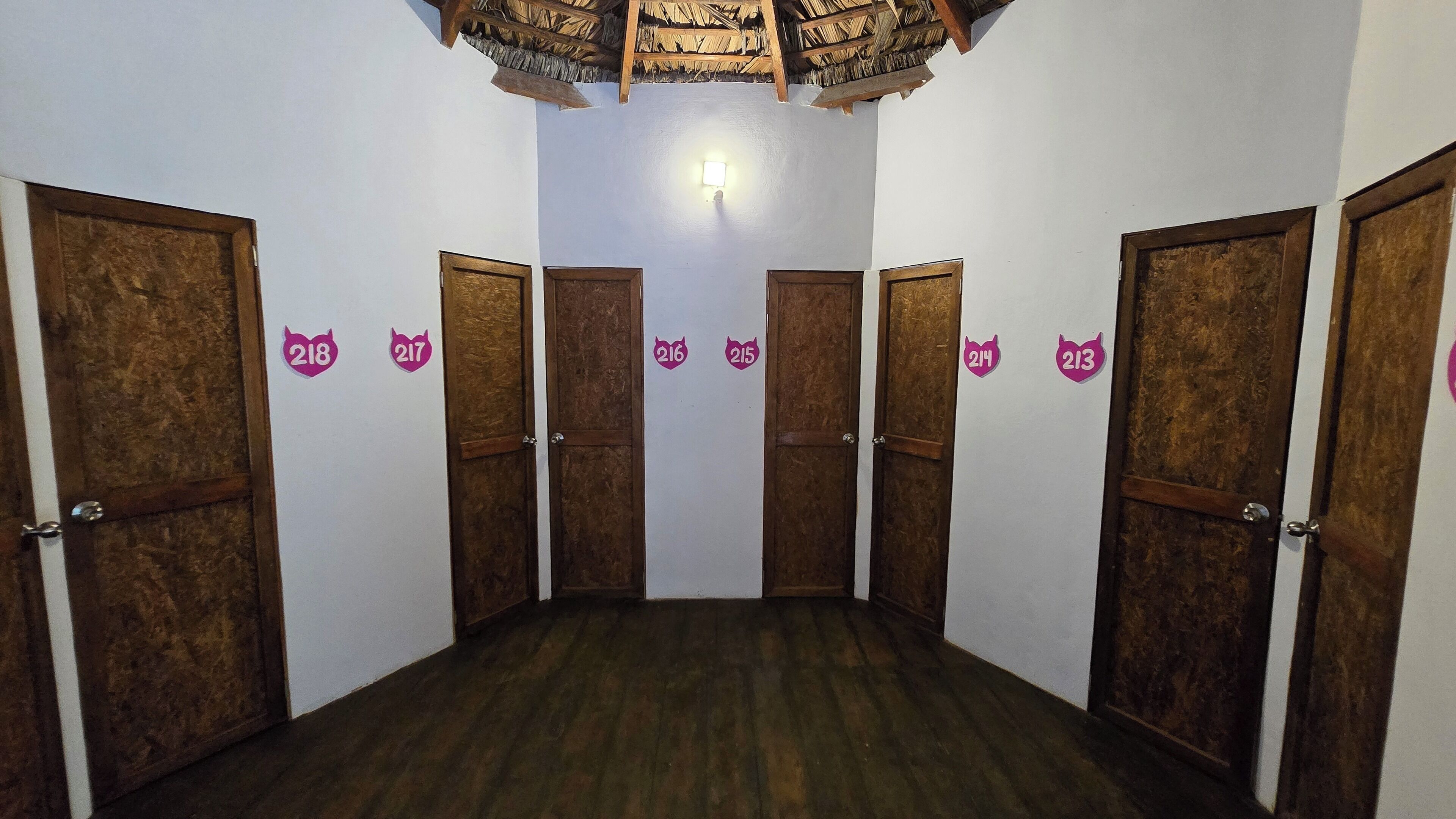 Um corredor com portas de madeira numeradas de 218 a 217, de 216 a 215, de 214 a 213 e de 212 a 211.