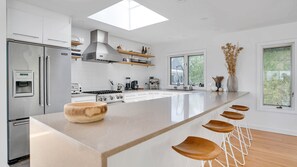 Una cocina moderna con una isla grande, electrodomésticos de acero inoxidable y un tragaluz.