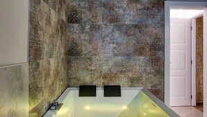 Une salle de bain moderne avec une baignoire sur pieds, un mur à texture et une porte blanche.