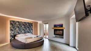 Une chambre à coucher moderne avec un lit aux lignes courbes, une cheminée et une grande fenêtre.