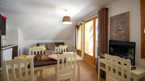 Ein gemütliches Loft-Zimmer mit Essbereich, Fernseher und großem Fenster.