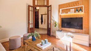 Una sala de estar con un mueble bajo de madera para el televisor, un televisor de pantalla plana y una mesa de centro con adornos.