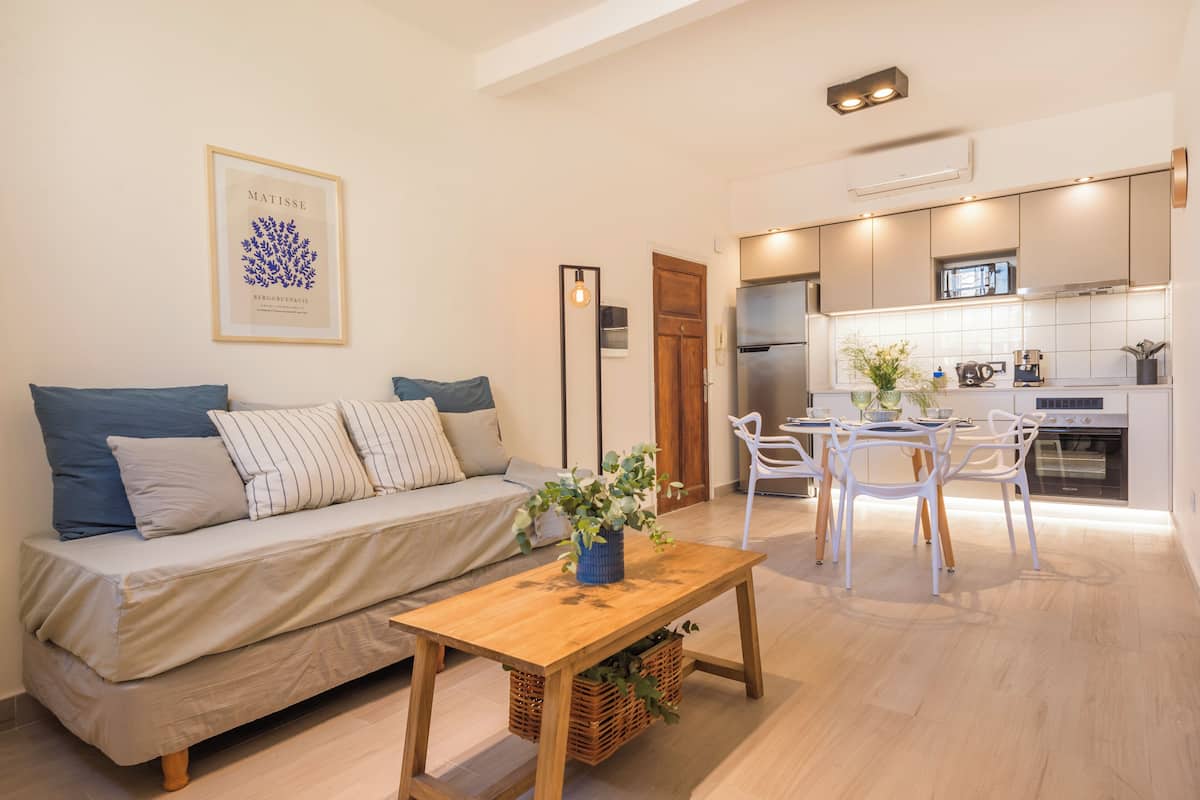 A modern living room with a sofa, a wooden coffee table, and a dining area with chairs and a table.