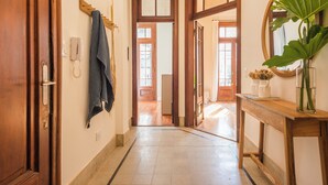 Un pasillo con puertas de madera, una toalla colgada, un teléfono y un espejo con una planta.