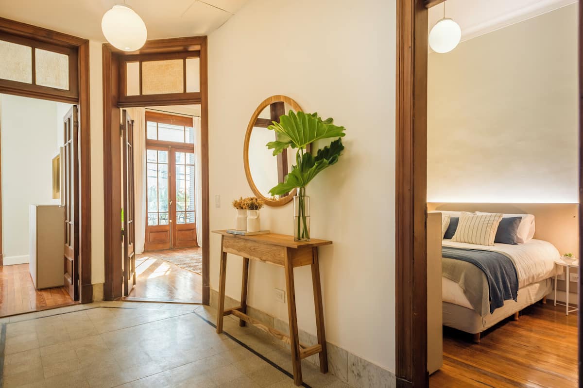 A hallway with a wooden console table, a large mirror, and a potted plant.