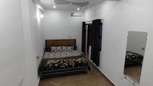 Un dormitorio con cama, ventilador de techo, espejo y puerta.
