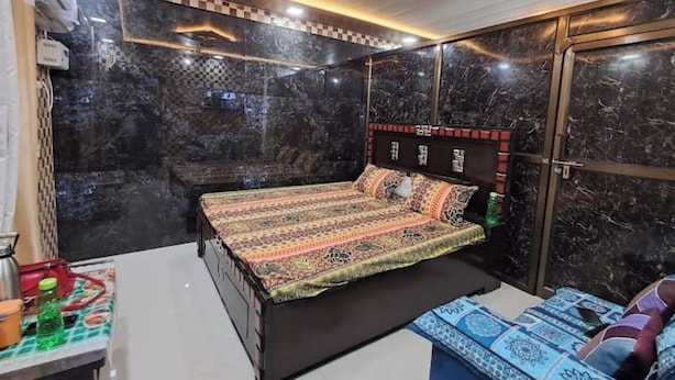Un dormitorio con cama, una mesita de noche y un banco con cojines.