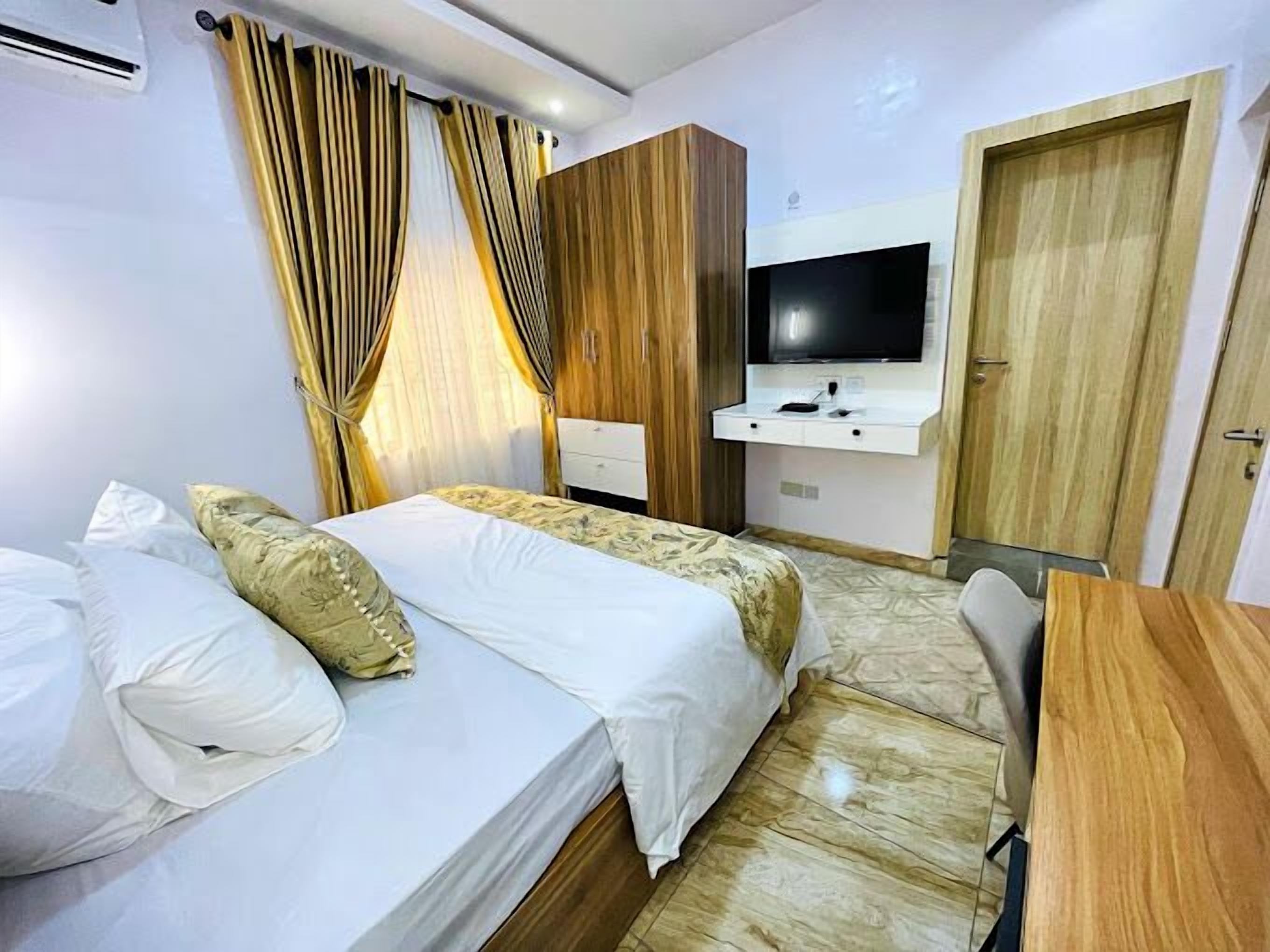 Een hotelkamer met een bed, een bureau, een televisie en een kledingkast.