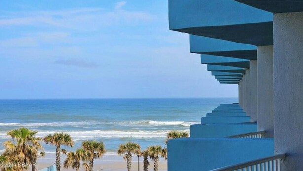Een balkon met uitzicht op de oceaan en palmbomen.