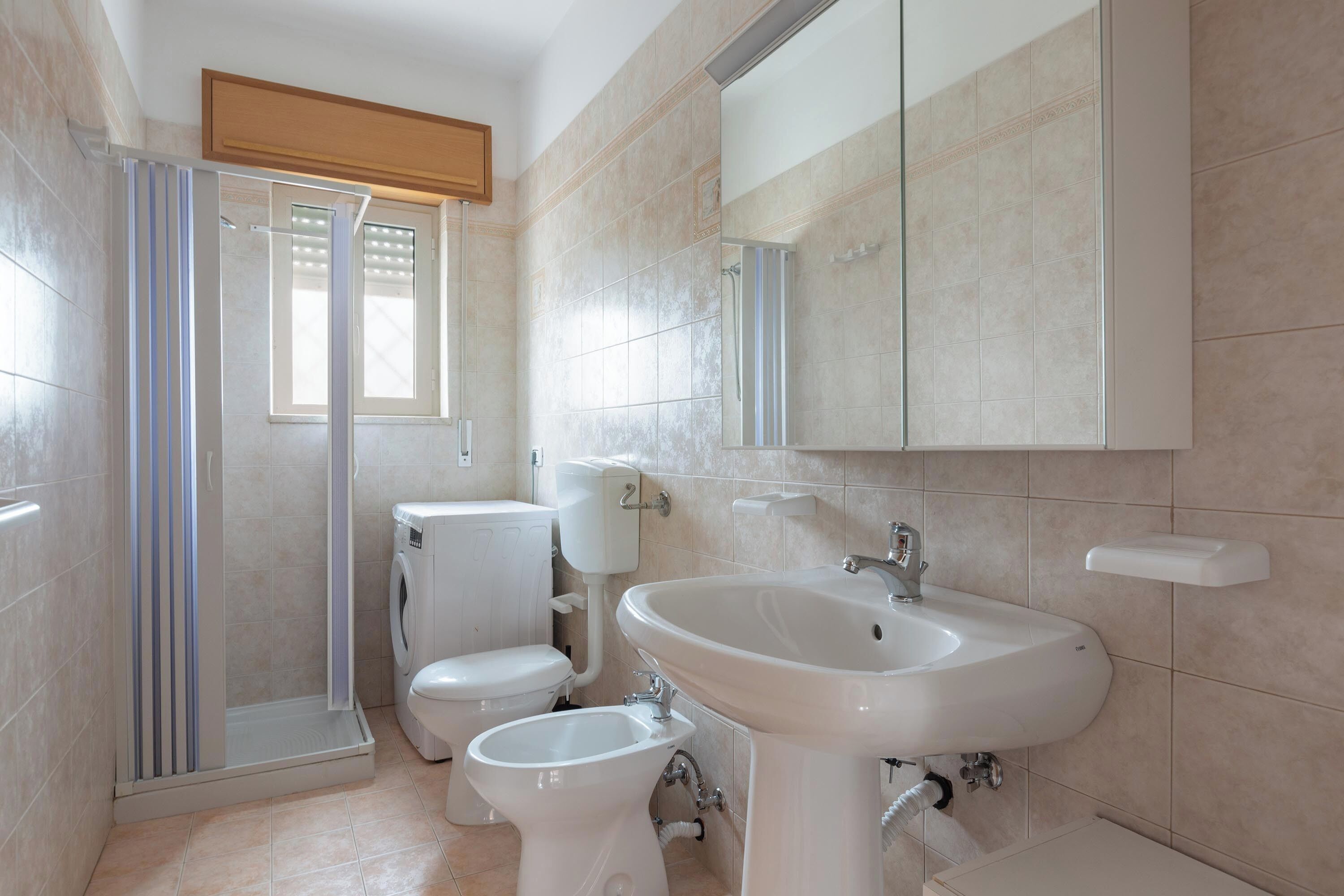 A modern bathroom with a shower, toilet, bidet, and sink.