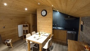 Um interior acolhedor em madeira, com sala de jantar, cozinha e sala de estar.