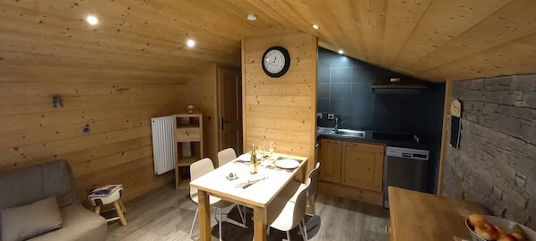 A cozy wooden interior with a dining area, a kitchen, and a living space.