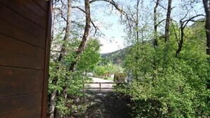 Uma cabana de madeira com varanda, com vista para uma área arborizada e uma montanha ao longe.