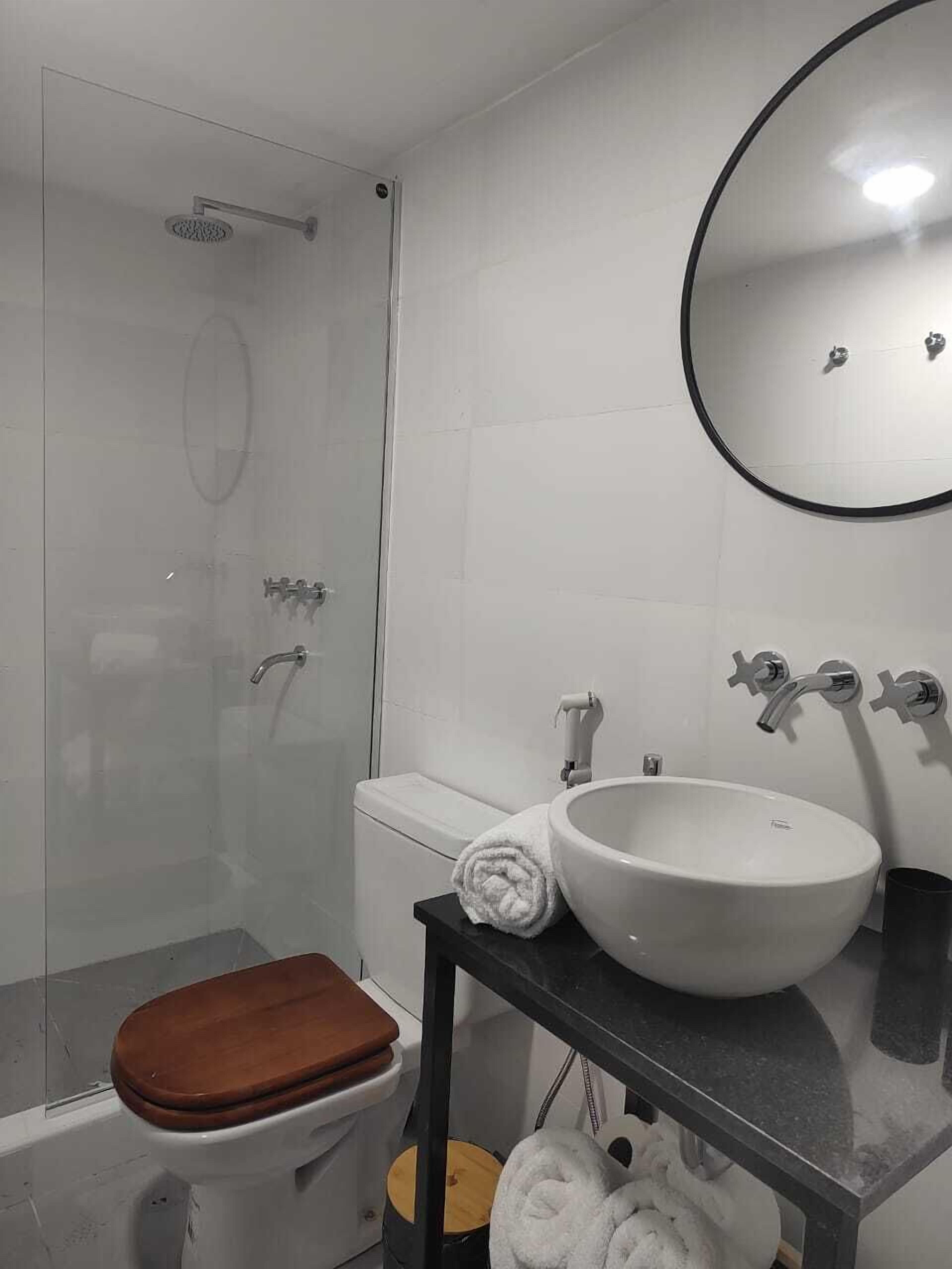 A bathroom with a toilet, a sink, a mirror, and a shower.