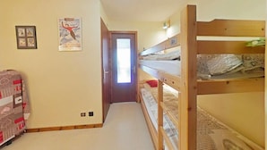 A narrow hallway with bunk beds on one side and a door at the end.